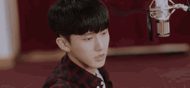 a young man is sitting in front of a microphone in a room .
