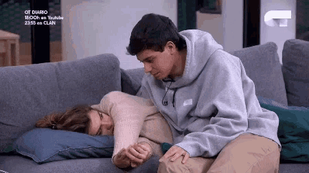 a man and a woman are sitting on a couch holding hands and hugging .