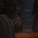 a group of people are standing in a dark room with a blanket on their backs .