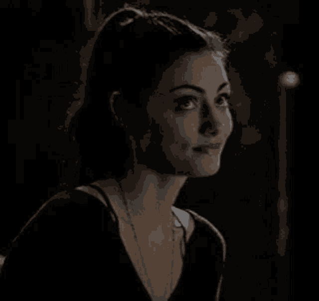 a close up of a woman 's face in a dark room with a ponytail .