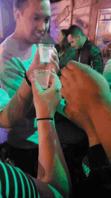a group of people toasting with shot glasses in a dark room