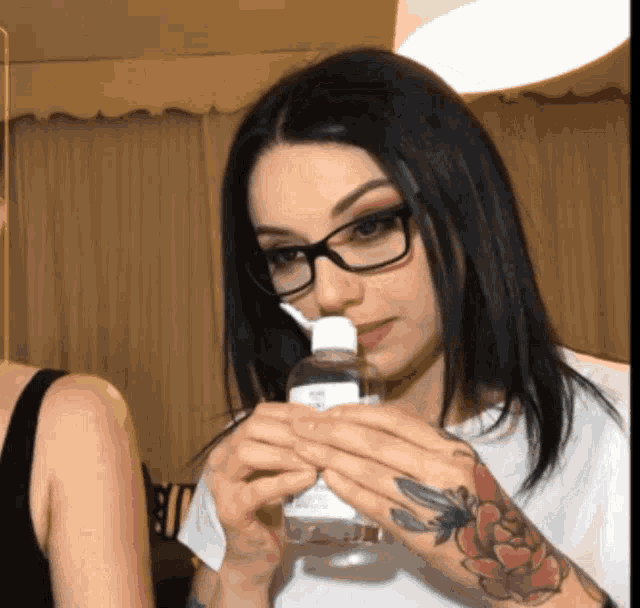 a woman wearing glasses is holding a bottle of hand sanitizer