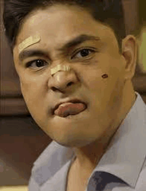a man with a bandage on his face is making a funny face .