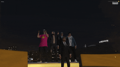 a group of people stand in front of a vinewood sign