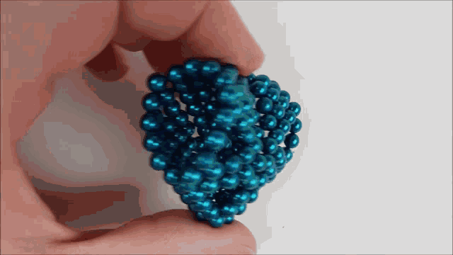 a person is holding a sphere made of blue beads