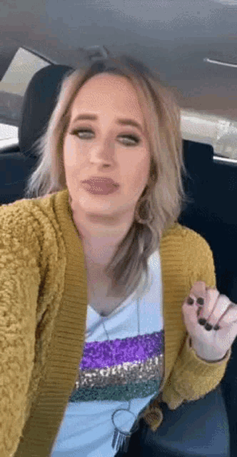 a woman in a car wearing a yellow sweater