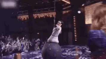 a woman is dancing on a pole in front of a crowd at a concert .
