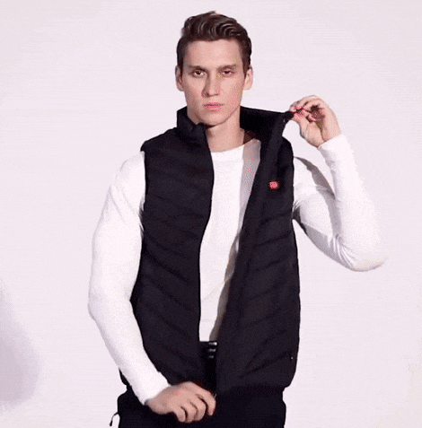 a man wearing a white sweater and a black vest is taking off his vest .