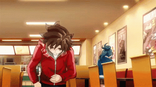 a man in a red hoodie is standing in a restaurant holding his stomach .