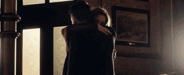 a man and woman hugging in front of a window