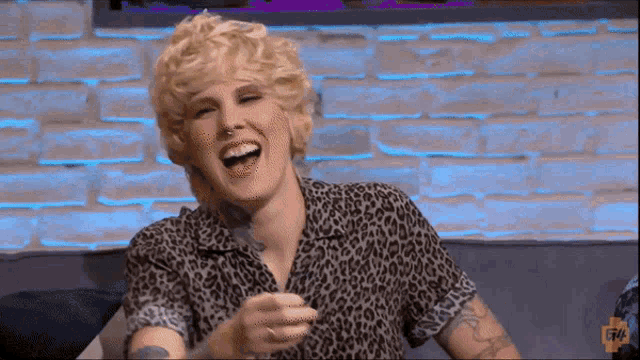 a woman wearing a leopard print shirt is laughing while sitting on a couch