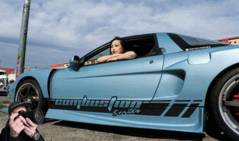 a woman leans out of the window of a blue car that says combustion series