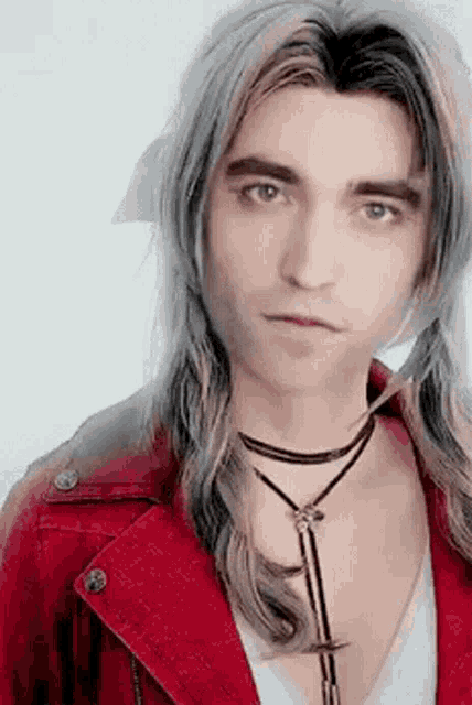 a man with long grey hair is wearing a red jacket and a necklace
