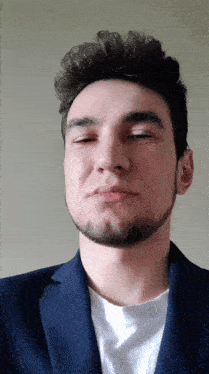a man with a beard wearing a blue jacket and white shirt