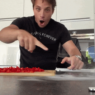 a man wearing a black shirt that says " dives forever " is cutting strawberries