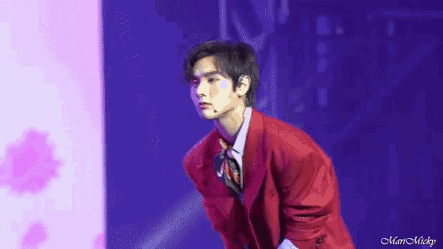 a young man in a red suit is standing on a stage .