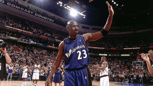 a basketball player wearing a wizards jersey waves to the crowd