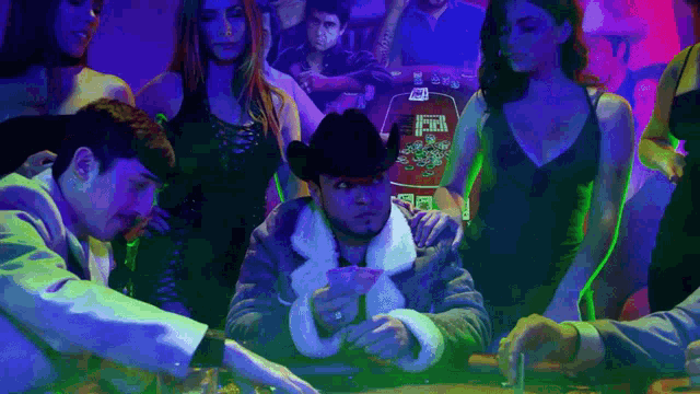 a man in a cowboy hat sits at a poker table