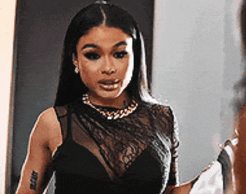 a woman is standing in front of a mirror wearing a black lace top and a gold necklace .