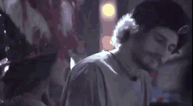a man with a beard is standing in a dark room with headphones on .
