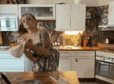 a woman in a floral dress stands in a kitchen