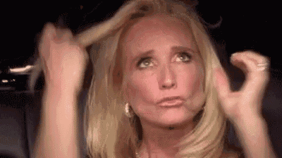 a woman is holding her hair in her hands while making a face .