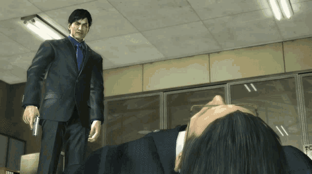 a man in a suit and tie standing next to another man laying on the floor