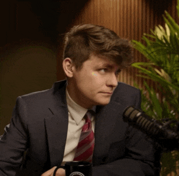 a man in a suit and tie is sitting in front of a microphone and holding a mug that says ' washington '
