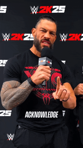 a man with a beard is holding a microphone in front of a wall that says w2k25