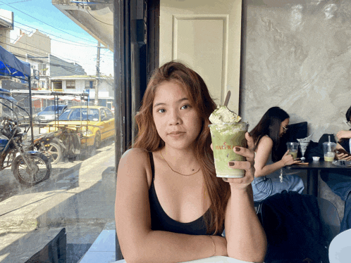 a woman is holding a cup of green tea