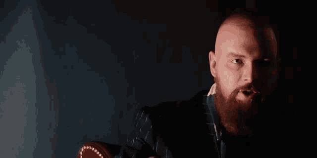 a man with a beard is sitting in a chair with the words " shoutouts an die bosscock bubble " above him