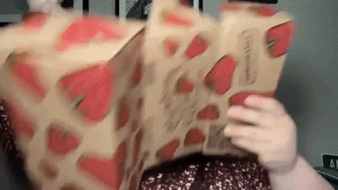 a person is holding a cardboard box with hearts on it in their hands .