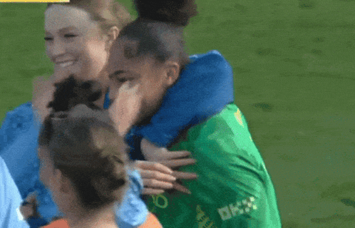 a woman hugging a man in a green shirt that says ' ok ' on it