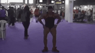 a muscular man is standing on a purple carpet in front of a crowd .