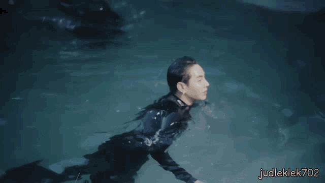 a man in a wet suit is swimming in a pool with judleklek702 written in the corner