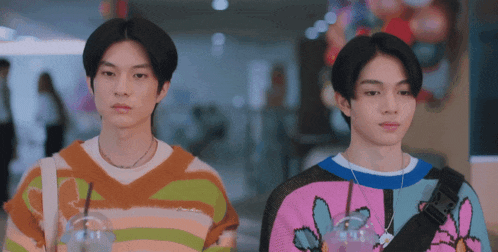 two young men wearing colorful sweaters are standing next to each other in a mall