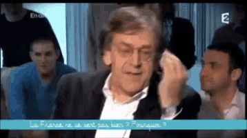 a man in a suit is talking to a group of people with the number 2 on the bottom of the screen