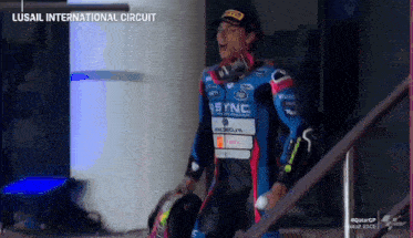 a motorcycle racer is walking down a set of stairs with the words lusail international circuit on the bottom
