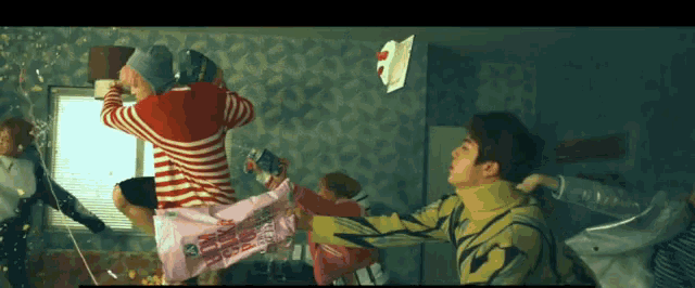 a group of people are fighting in a room and one of them is wearing a red and white striped shirt .