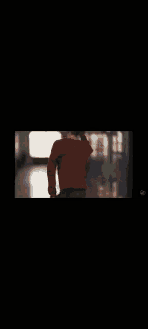 a person wearing a red sweater is walking down a hallway .
