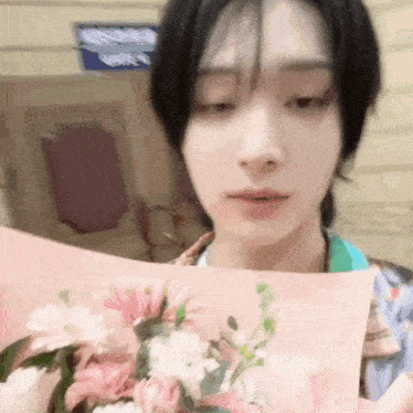 a young man is holding a bouquet of pink flowers in his hand .