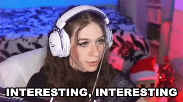 a girl wearing headphones is sitting in front of a computer and says interesting , interesting .