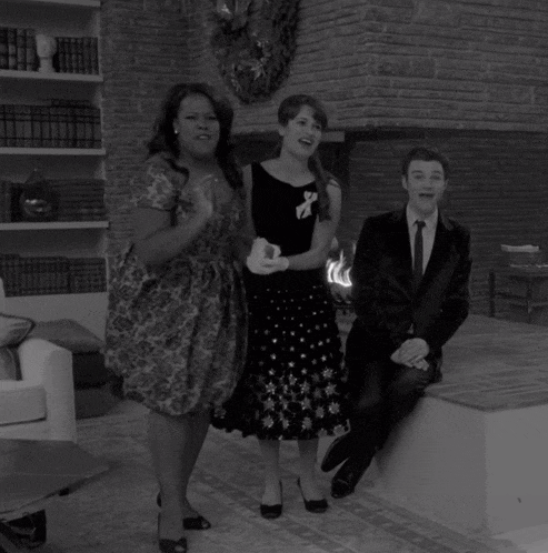 a man in a suit sits on a couch next to two women