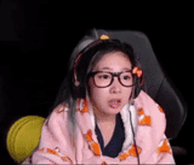 a girl with glasses and headphones is sitting in a chair .