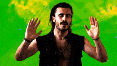 a man with a beard is standing in front of a green screen with his arms outstretched