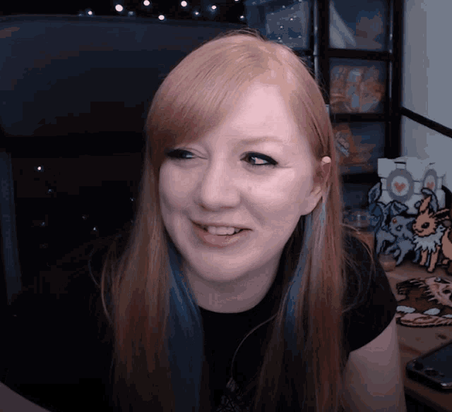 a woman with red hair and blue highlights is smiling in front of a sign that says " i love you "