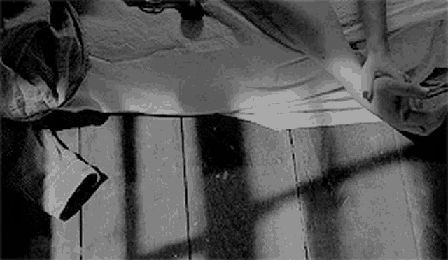 a black and white photo of a person laying on a wooden floor .