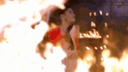 a woman is standing in the middle of a fire .