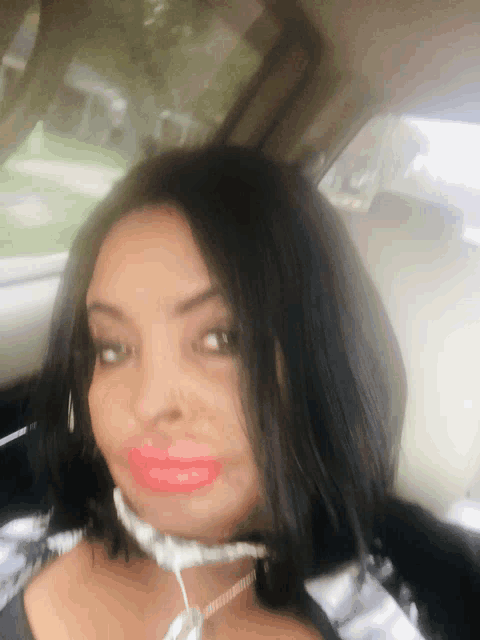 a woman in a car with red lips and ear buds around her neck