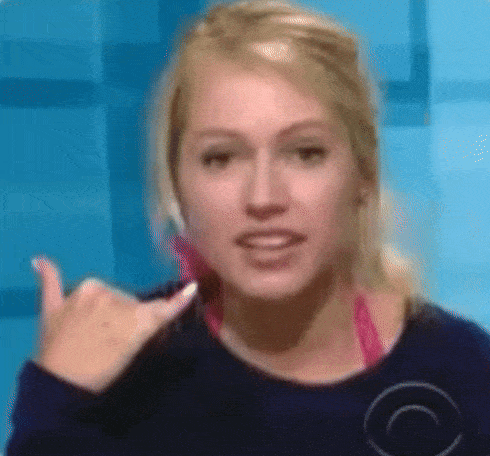 a woman is giving a thumbs up sign while wearing a blue shirt
